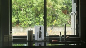 A kitchen with a window view of greenery, a knife holder, a soap dispenser, and a faucet. - PLUFINO RESORT VILLA (Ise)