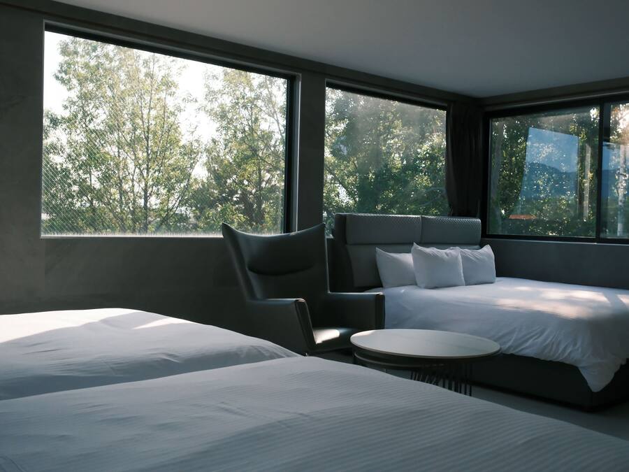 Una habitación de hotel moderna con una cama grande, otra más pequeña, un área de descanso y una mesa redonda.