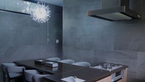 A modern kitchen with a central island, dark countertops, and a built-in stove. - PLUFINO RESORT VILLA (Ise)
