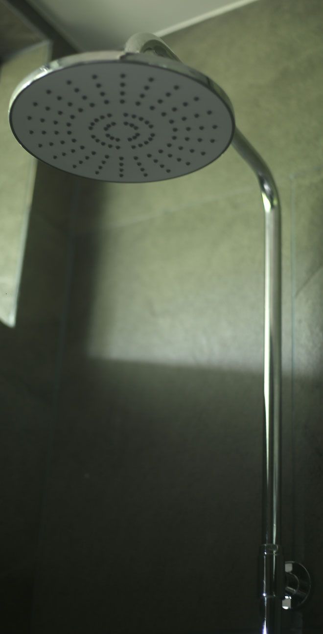 Un cabezal de ducha con diseño circular y un mando largo y recto.