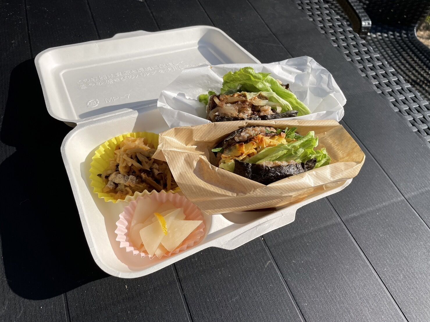 A takeout container with food items including a sandwich and a salad.
