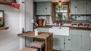Een landelijke keuken met houten werkbladen, een gootsteen en een raam.