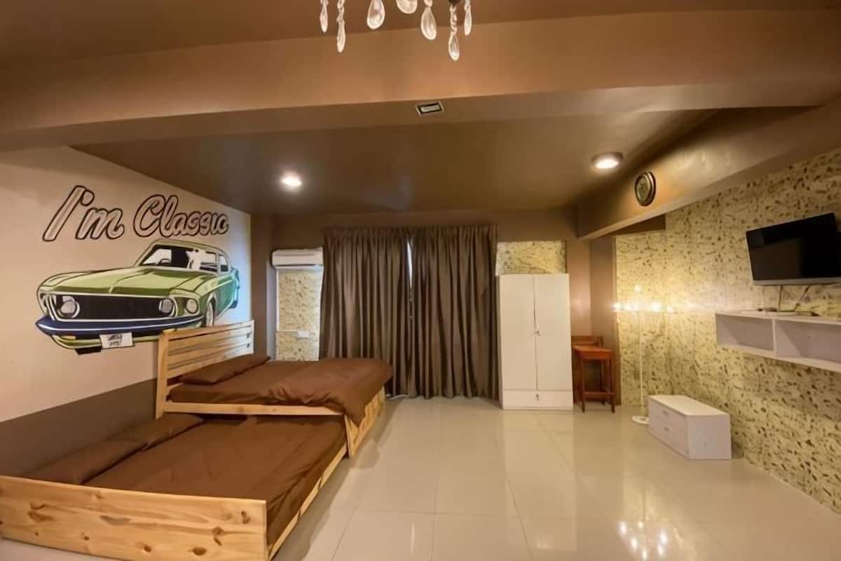 A room with a bunk bed, a wall-mounted TV, a wardrobe, and a window with curtains.