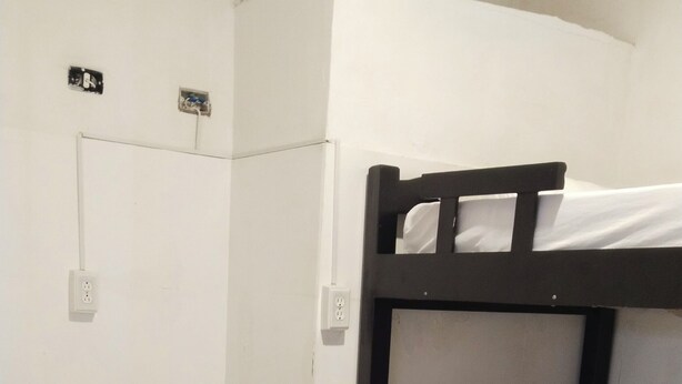 A bunk bed room with a white mattress and a single bed. There are electrical outlets on the wall. - shanty guest house (Cartagena)