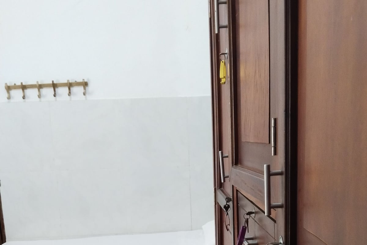 A hotel room with a bed, a wardrobe, and a wall-mounted coat rack.