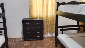 A room with two bunk beds, a small black dresser with drawers, and a curtain with a floral pattern. - shanty guest house (Cartagena)