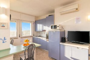 Une cuisine compacte équipée d’un four à micro-ondes, d’un évier et d’un téléviseur à écran plat posé sur un plan de travail.