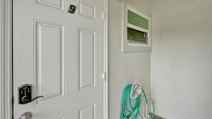 A white door with a lock, a window, and a coiled cable on the wall.