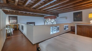 Un dormitorio con techo de madera, una cama, un escritorio y una ventana con rejas decorativas de hierro.