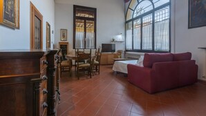 Una habitación con una mesa de comedor, sillas, un sofá, un televisor y una ventana con cortinas.
