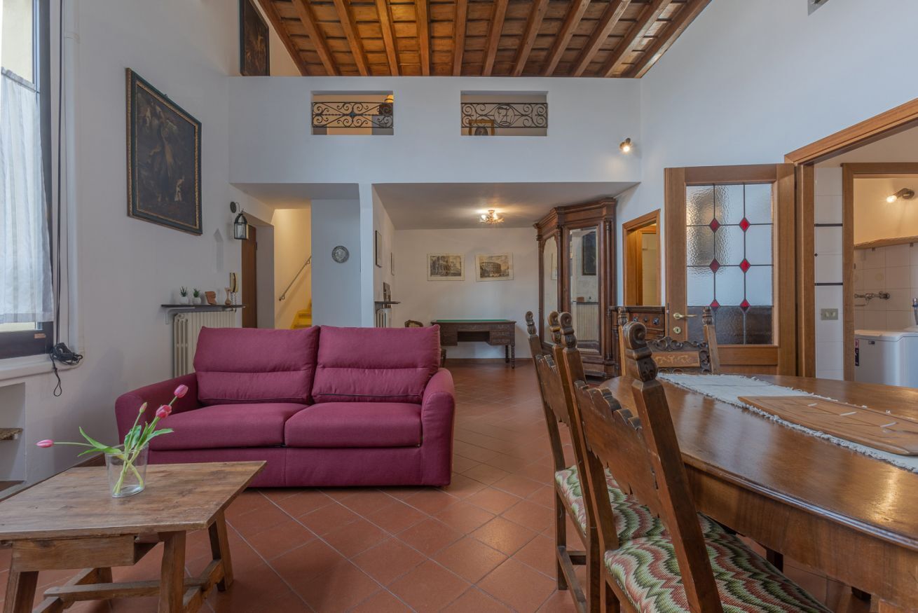 A living room with a sofa, wooden dining table, and chairs.