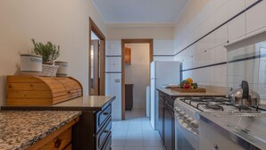 Una cocina con encimera de granito, armarios de madera, estufa de acero inoxidable y refrigerador.