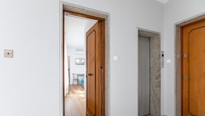 Un couloir avec des portes en bois, un ascenseur bien visible et un sol carrelé.