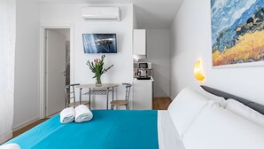 Une chambre d’hôtel équipée d’un lit, d’un bureau, d’une chaise, d’une petite table, d’un four à micro-ondes, d’un tableau et d’un appareil de climatisation.
