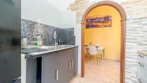 A kitchen with a tiled backsplash, a sink, and a dining area with a table and chairs.