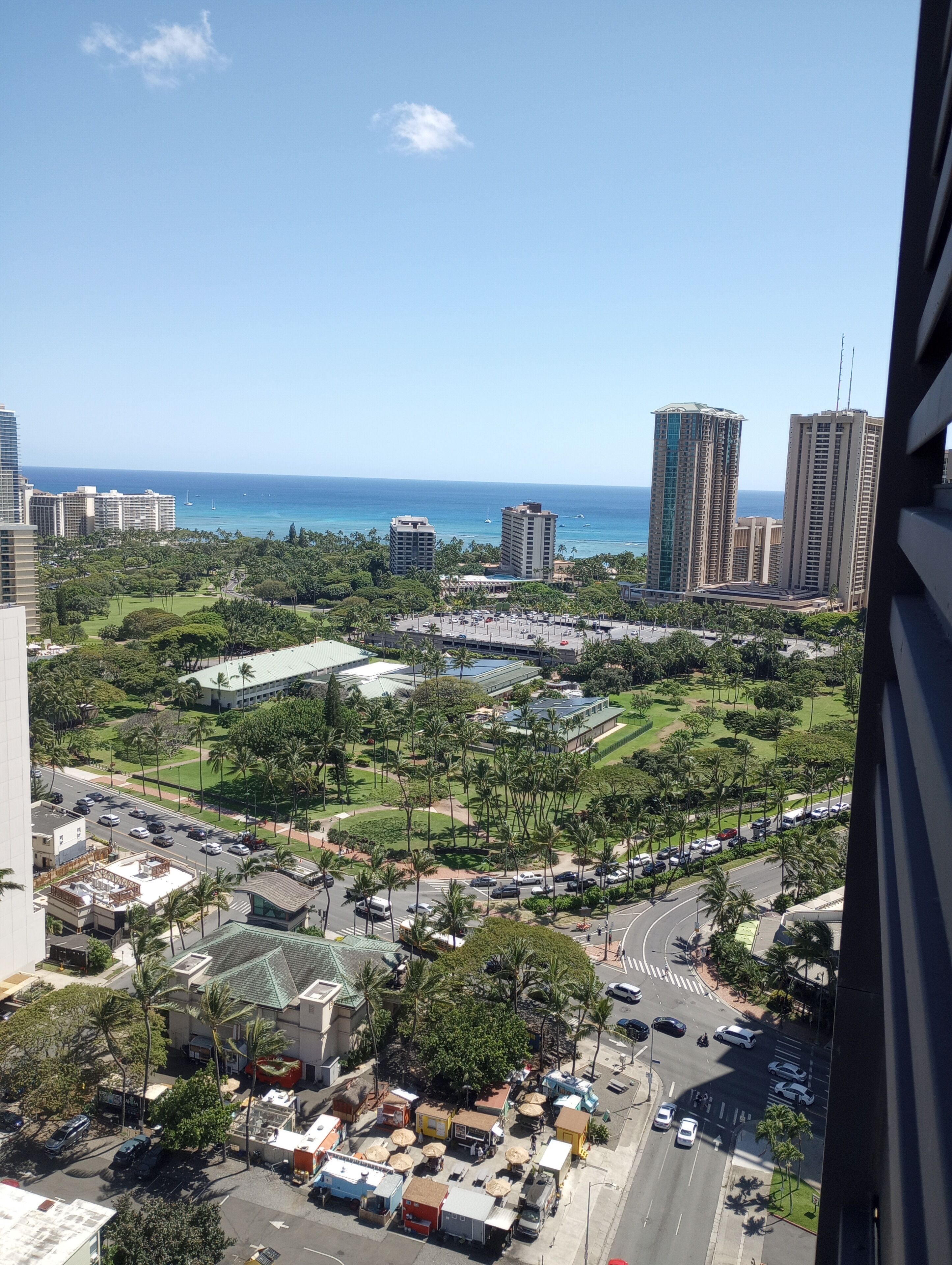 Un edifici de grans alçades amb vista a una ciutat costanera, incloent un port esportiu i edificis alts.