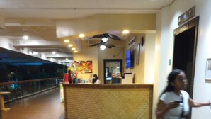 A hotel corridor with a reception desk, a ceiling fan, and a wall-mounted television. - Cozy studio condo in wonderful Honolulu with WiFi, fitness room (Honolulu)