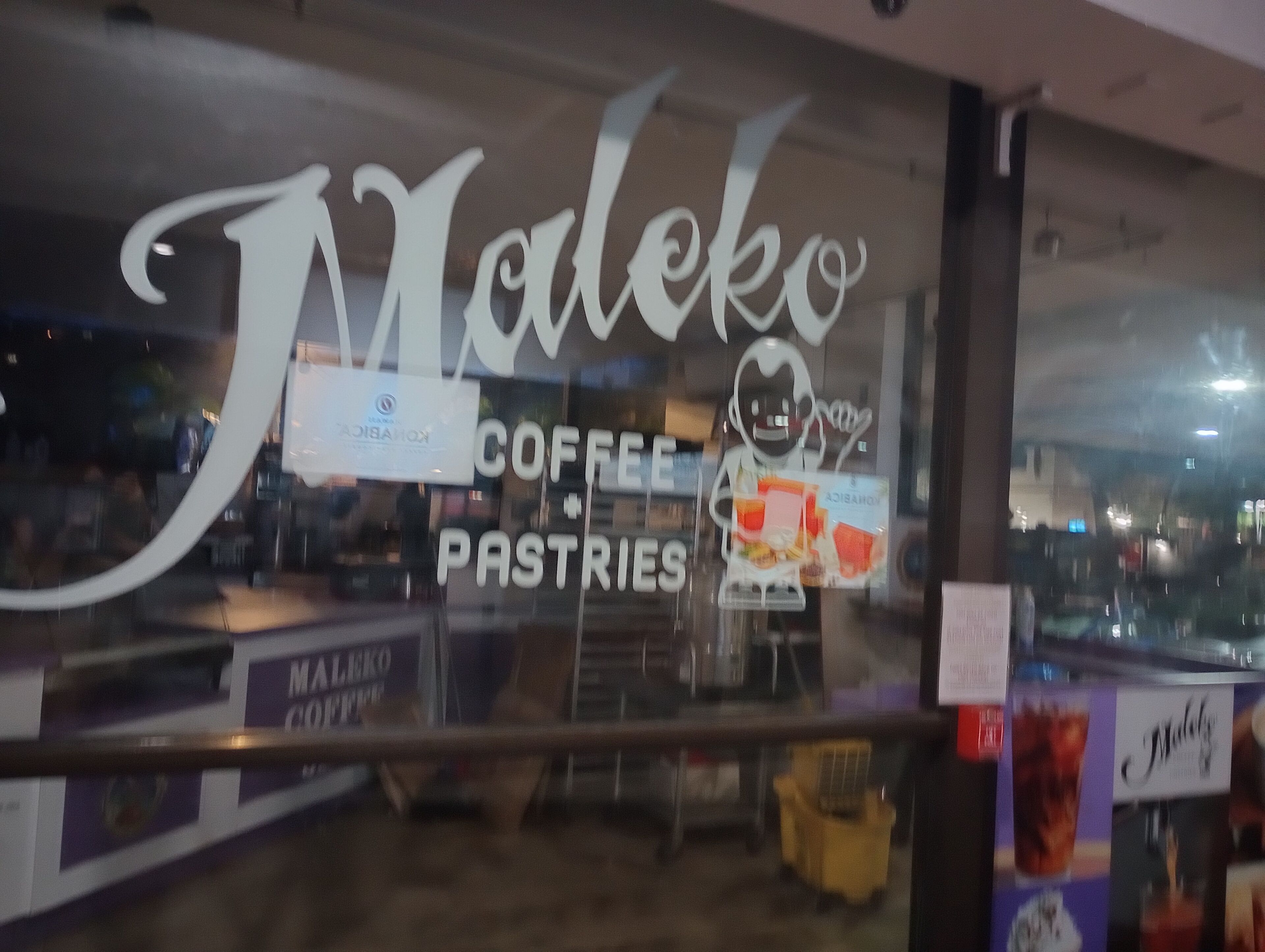 A coffee shop window with the name 'Maleko' and menu items like coffee and pastries.