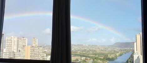 Une chambre d’hôtel avec vue sur la ville et un arc-en-ciel.