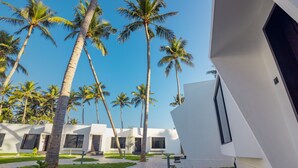 A modern resort with white buildings, palm trees, and a paved walkway. - The Saravi Resort (Vanur)