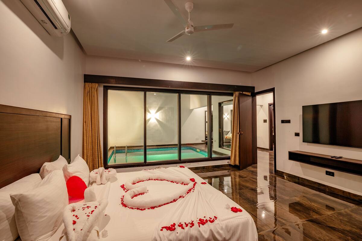 Habitación de hotel con cama, televisión, ventilador de techo y vista a una piscina.