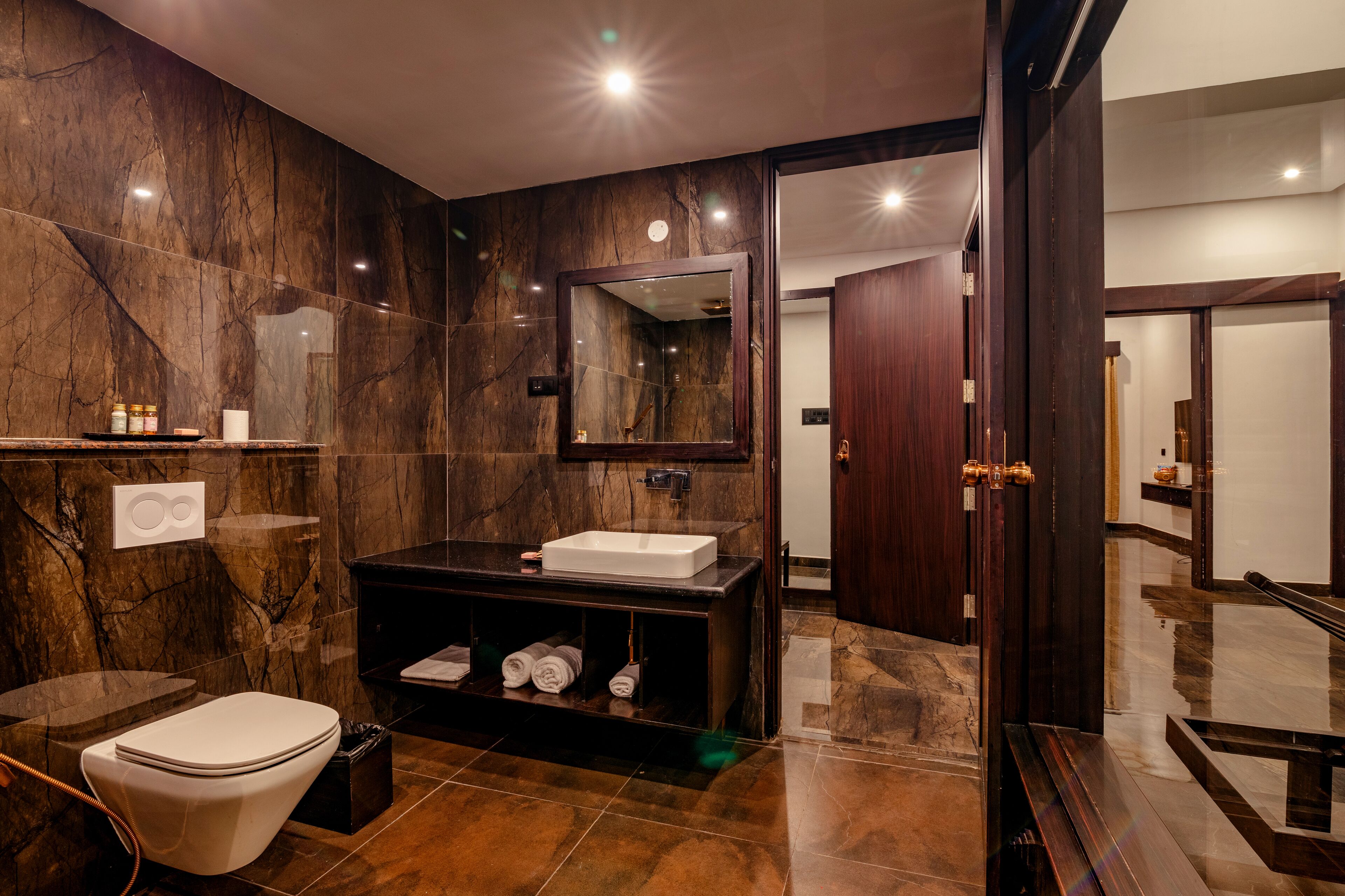 A modern bathroom with a marble wall, a white sink, and a toilet.