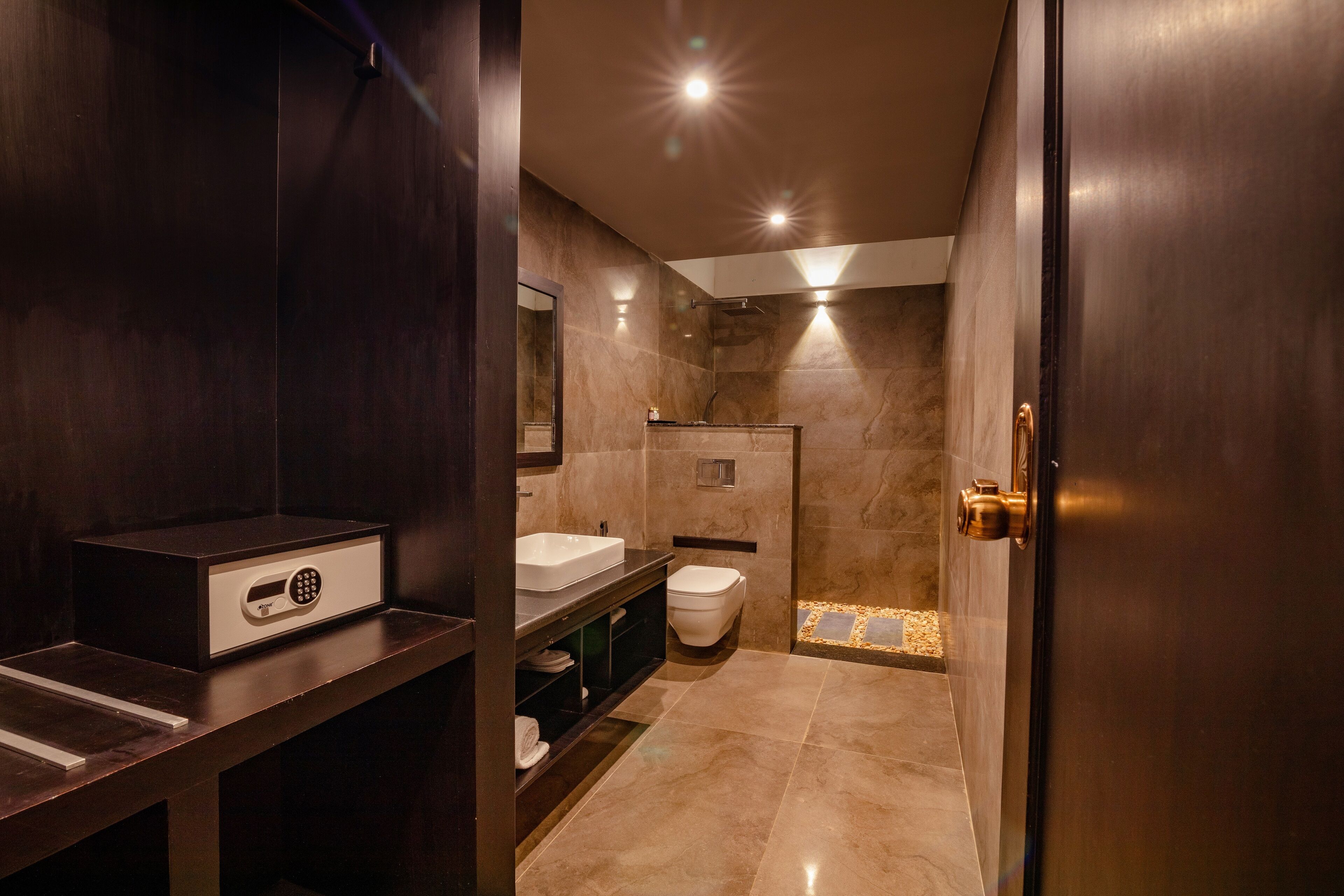 A modern bathroom with a dark wood vanity, a white sink, and a toilet.