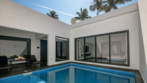 A modern pool area with a clear blue pool, large sliding glass doors, and a white exterior wall. - The Saravi Resort (Vanur)