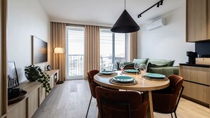 A modern kitchen with a dining area, a sofa, and a TV. - Cuero | Centrum | Garaż podziemny | Dwie sypialnie (Bydgoszcz)