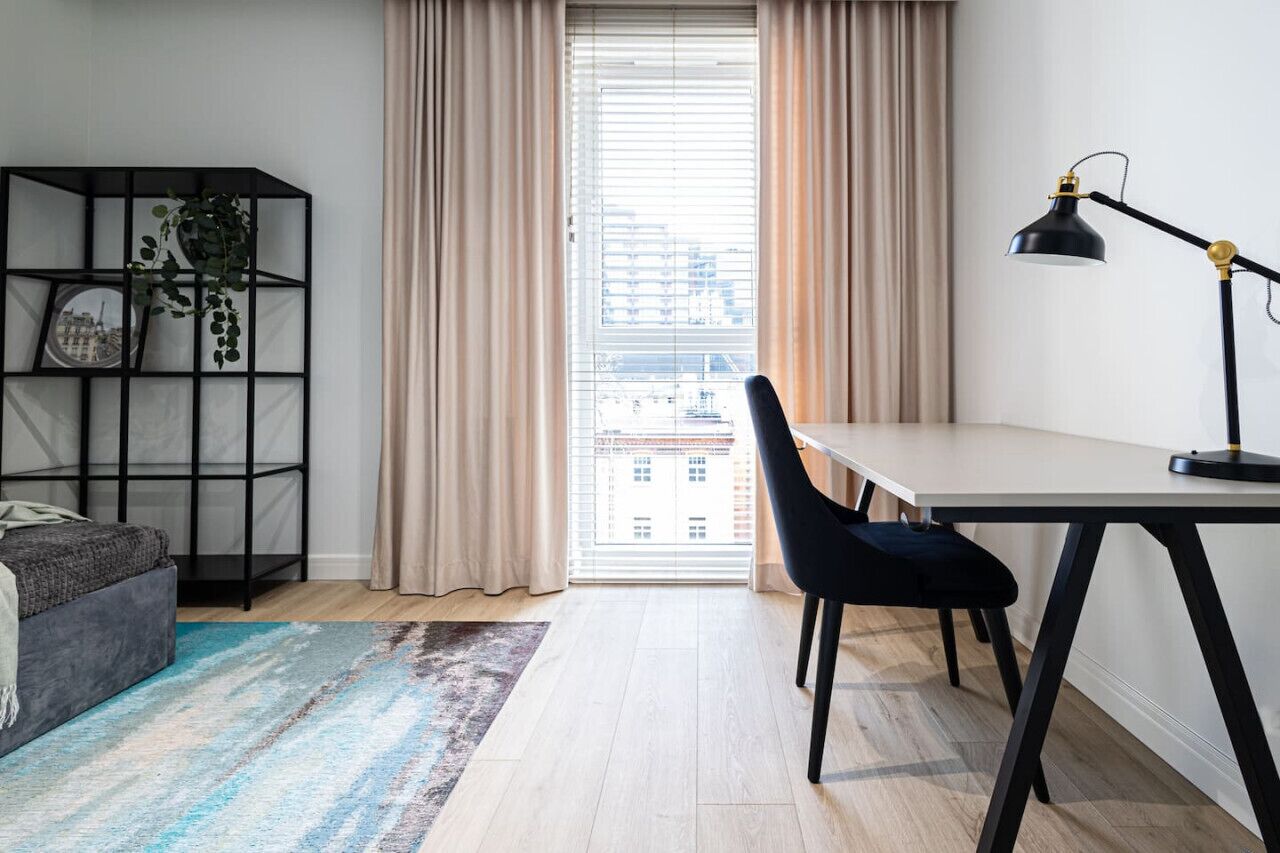 Habitació moderna amb escriptori, cadira i prestatgeria.
