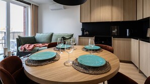 A modern dining area with a round wooden table set for four, surrounded by brown chairs. - Cuero | Centrum | Garaż podziemny | Dwie sypialnie (Bydgoszcz)