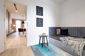 Una habitación moderna con un sofá gris, una pequeña mesa redonda con plantas y una alfombra azul estampada.