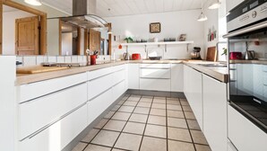Une cuisine moderne avec des meubles blancs, un carrelage au sol et des appareils électroménagers en acier inoxydable.