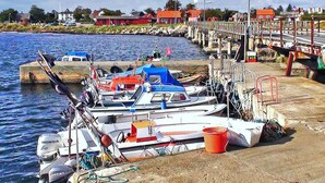 Un port de plaisance avec plusieurs bateaux amarrés, une jetée s’avançant dans l’eau et des bâtiments en arrière-plan.