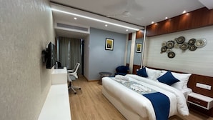 A modern hotel room with a large bed, a desk, a chair, and a television.