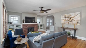 A living room with a fireplace, a ceiling fan, a TV, and a large abstract painting. - 2 Living Areas & Kids' BunkRoom (Springfield)