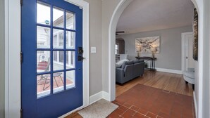 A blue door with a glass panel, a living room with a gray sofa, a stone accent wall, and a tiled floor. - 2 Living Areas & Kids' BunkRoom (Springfield)