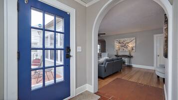 A blue door with a glass panel, a living room with a gray sofa, a stone accent wall, and a tiled floor.
