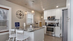 A modern kitchen with white cabinetry, a central island with bar stools, stainless steel appliances, and pendant lighting. - 2 Living Areas & Kids' BunkRoom (Springfield)