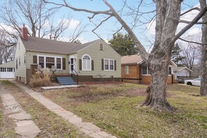 A two-story house with a front porch, a chimney, and a large tree in the yard. - 2 Living Areas & Kids' BunkRoom (Springfield)
