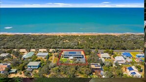 An aerial view of a coastal area with a large building surrounded by greenery and a beach in the background. - Escape to Paradise - Beach views 5bedrooms, 2 Kitchens, 2 Living, 2 Bathrooms (Paradise Beach)