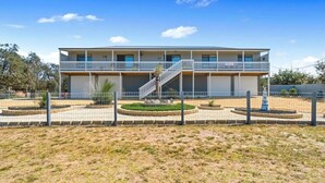 A two-story building with a central staircase, surrounded by a fenced garden area. - Escape to Paradise - Beach views 5bedrooms, 2 Kitchens, 2 Living, 2 Bathrooms (Paradise Beach)