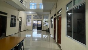 A spacious hallway with a polished floor, a wooden desk, and a chair, leading to a door with a window. - Hotel O Pondok Ibu SyariahNearEco Edu Park (Pekanbaru)