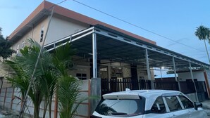 A building with a covered parking area and a white car parked in front. - Hotel O Pondok Ibu SyariahNearEco Edu Park (Pekanbaru)