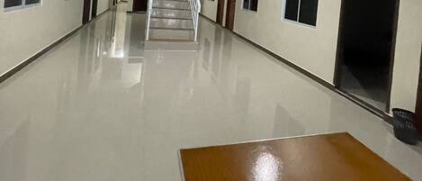 A long, empty hallway with a polished floor, a staircase, and doors leading to rooms.