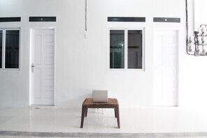 Three doors lead to separate spaces, a laptop sits on a small table, and a floor with an electrical outlet is visible.