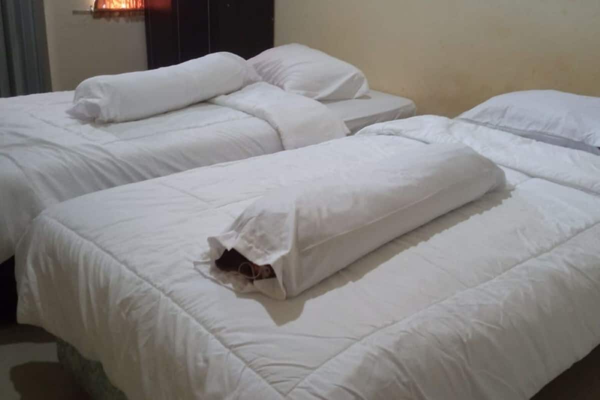 Een hotelkamer met twee bedden, elk voorzien van witte lakens en kussens.