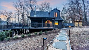 A modern house with a deck, a chimney, and a small shed. - Dreamtime Hillside Cabin w/ hot tub, fire pit, expansive deck (Hedgesville)