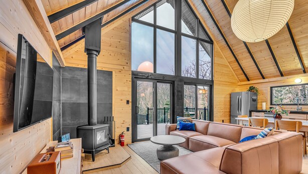 A modern log cabin interior with a large living area, a fireplace, and a kitchen.