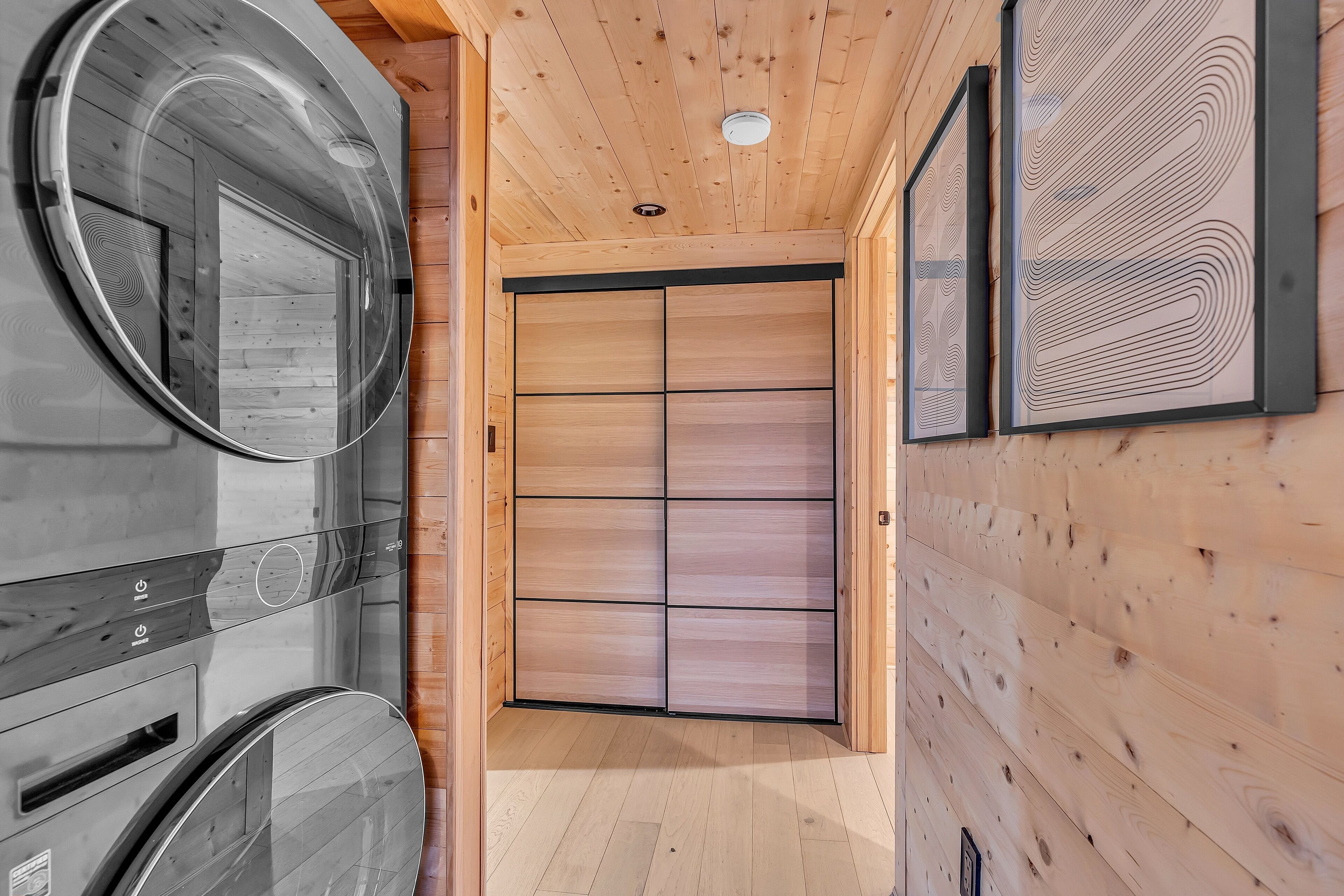 Een houten interieur met een sauna, een schuifdeur en een kunstwerk in een lijst.
